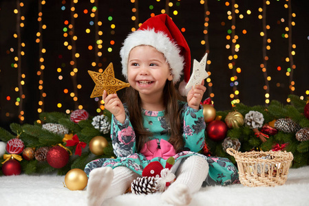 儿童女孩肖像中的圣诞装饰，快乐的情绪，冬天假日概念，深色背景照明和博克灯火
