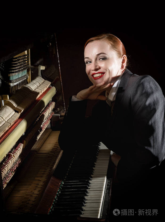 女音乐家身着勒芒西装坐在钢琴旁边
