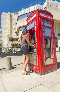 美丽的女人在伦敦红色电话亭