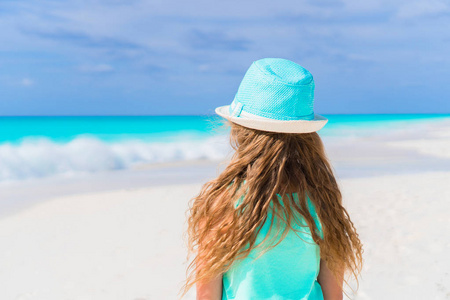 小女孩戴着帽子在加勒比地区度假期间在海滩散步