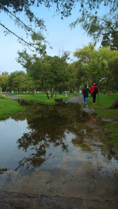 两名男子在雨后走在 La 卡罗莱纳州公园旁一大滩水。基多厄瓜多尔