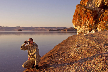 男人看起来在贝加尔湖岸边上双筒望远镜