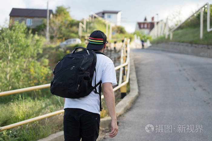 背包的时尚年轻男人独自行走在山路上