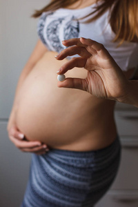 怀孕的女人和维生素药片在手的肚子