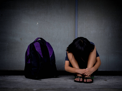 伤心的孩子坐在地板上等待父的书包照片