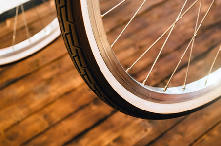 一辆时髦的自行车轮，有白色的轮辋，在时尚的木制背景上有一个棕色的橡胶轮胎。