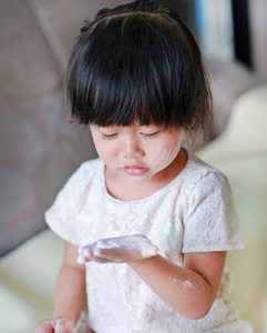 可爱的小女孩，她的脸上和手上的婴儿奶粉的画像。滑石粉概念