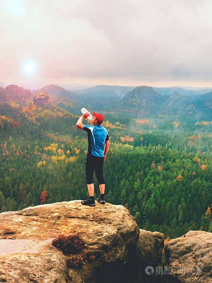 从塑料瓶蓝色和黑色运动服喝水口渴的徒步旅行者汗累的旅游