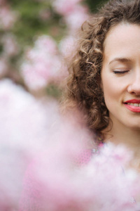 围绕着丁香粉色的花树在春天的花园中的女人