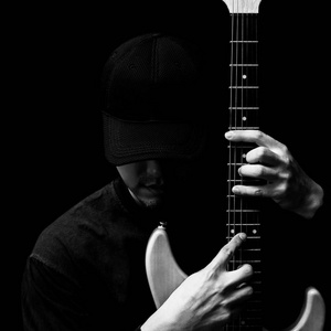 亚洲英俊的音乐家,在电吉他上摆姿势照片