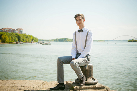 年轻的瘦男人,优雅时髦穿着白衬衫,裤子用吊带和领结摄影图