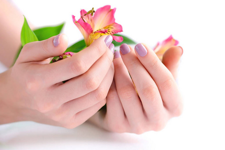 在白色背景上的钉子和花六出粉红色指甲与一个女人的手