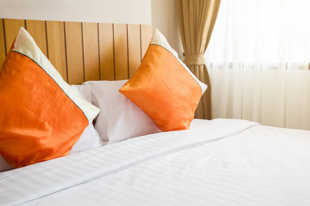 橙色的枕头和白毛毯与照明右上侧的卧室里的床上