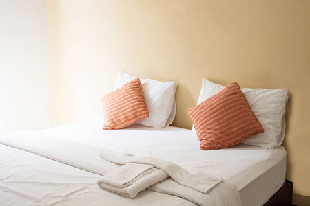 白色的枕头和橙色的枕头在床上，照明在早上在老式的卧室毯