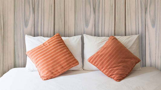 白色的枕头和橙色枕头在床上，用毯子