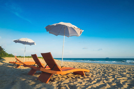 橙色的沙滩椅和在阴天蓝沙滩遮阳伞