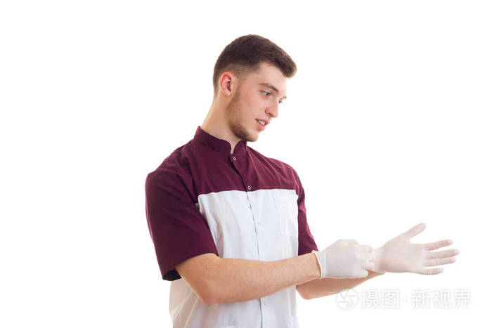 年轻医生站侧身,戴上白手套的手上孤立的白色背景