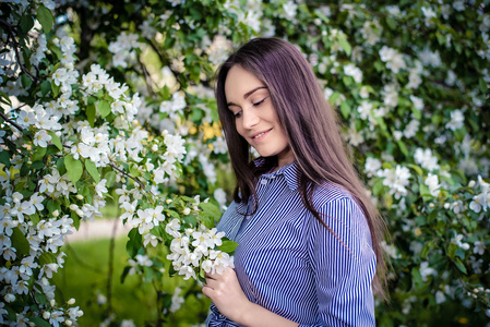 花朵盛开的苹果树身边的女孩低头