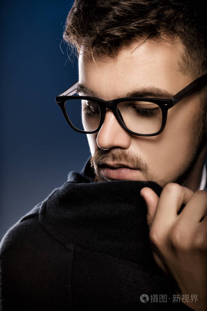 英俊的年轻男子戴着眼镜在蓝色背景上的肖像