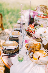 可爱的婚礼表设置在绿色阳光森林。侧面图的美味的食物和包在牛皮纸和绳子躺在白板下的木架子上的面包