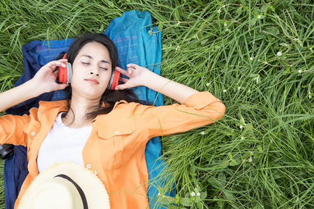 年轻女子躺在绿草地上自由和放松的概念