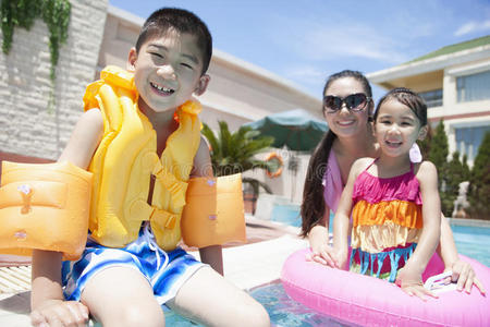 家庭肖像，母亲，女儿和儿子，在游泳池旁边，有游泳池玩具