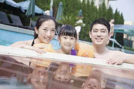 泳池边微笑的一家人看着镜头