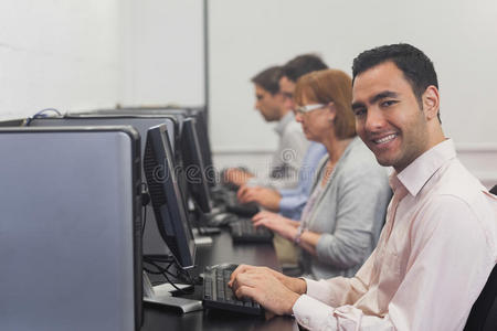 坐在电脑教室里的快乐成熟的学生