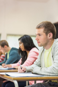 青年学生在课堂上写笔记