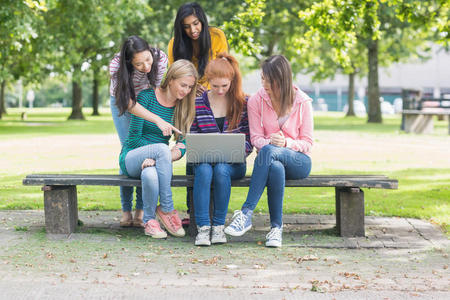 年轻的大学女生在公园里使用笔记本电脑