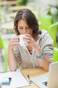 学生在自助餐桌边用笔记本电脑喝咖啡