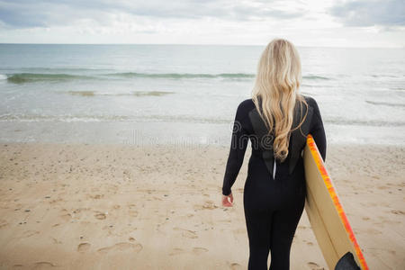 海滩带冲浪板的湿衣服女人的后视图