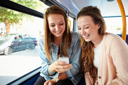 两个年轻女子在公共汽车上读短信