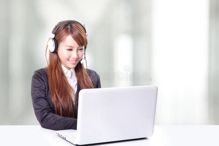 穿着西装的女性在笔记本电脑上打字并使用耳机