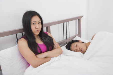不高兴的女人和睡在床上的男人的画像照片
