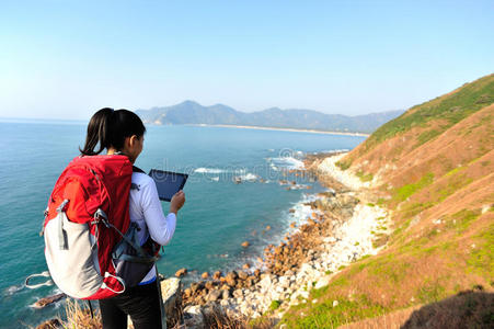 远足女子站在海边用数码平板电脑