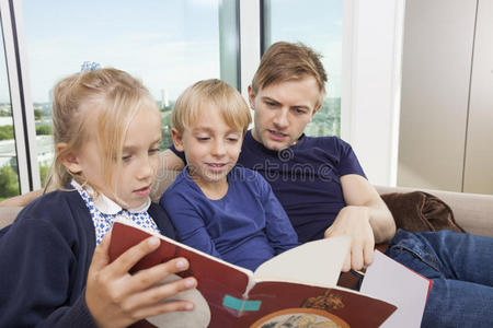 孩子在沙发上看ipad爸爸和孩子在家沙发上看故事书照片