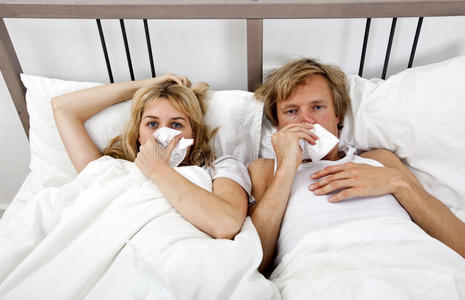 一对患感冒的夫妇躺在床上的画像