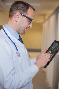 使用平板电脑的男医生。在医院走廊里。
