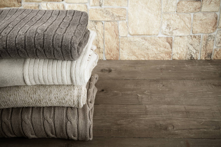 针织服装对面石质墙的木桌上一叠照片