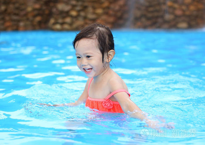 漂亮的小女孩在游泳池在户外玩耍