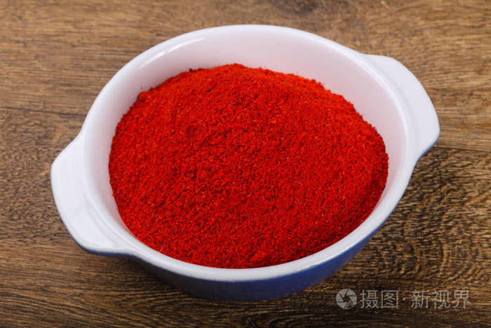 红椒粉堆在碗里的木制背景上