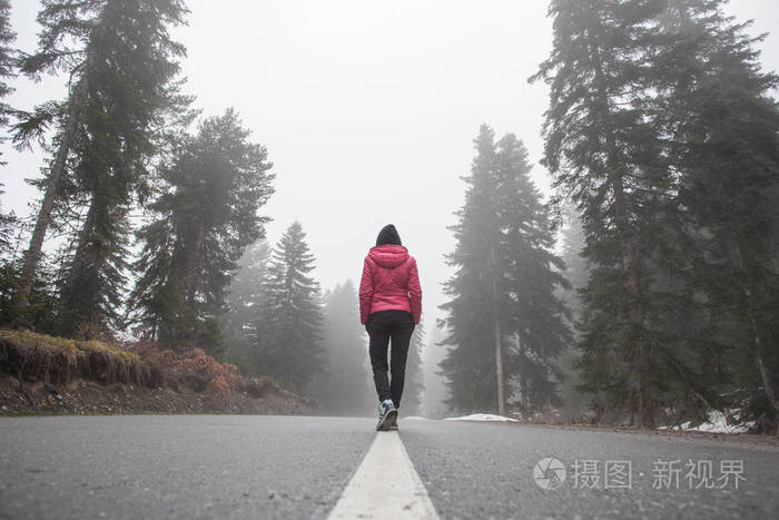 一个年轻的女孩站在朦胧的道路上