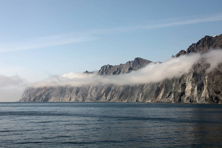 在晨雾中的鄂霍茨克海的岩石海岸