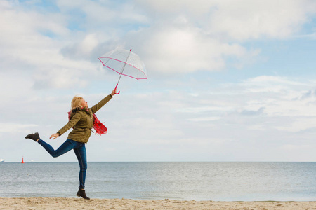 在海滩上跳跃着透明雨伞的女人