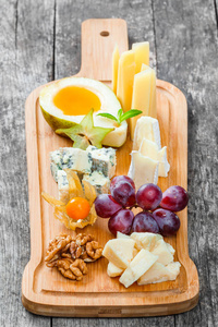 奶酪拼盘饰以梨 蜂蜜 核桃 葡萄 杨桃 酸浆在砧板上木制的背景上。小吃和酒开胃菜设置。顶视图