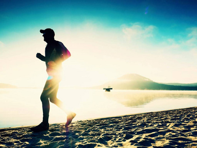 人在海边跑黄昏时分。运行在海边的跑步运动员。运动员健身剪影