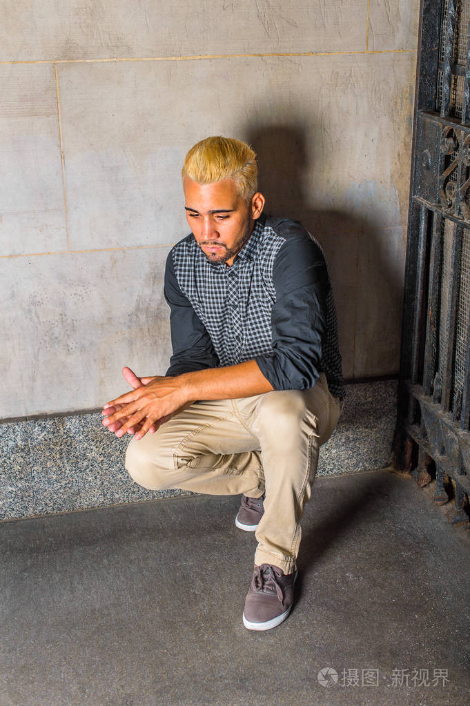 不快乐年轻的西班牙裔美国人蹲在角落里想