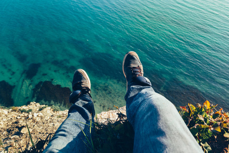 在风景如画的海景徒步旅行放松概念的背景下, 男人的腿穿着运动鞋
