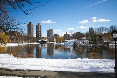 反射的湖路和树在中央公园和大厦与雪和蓝天